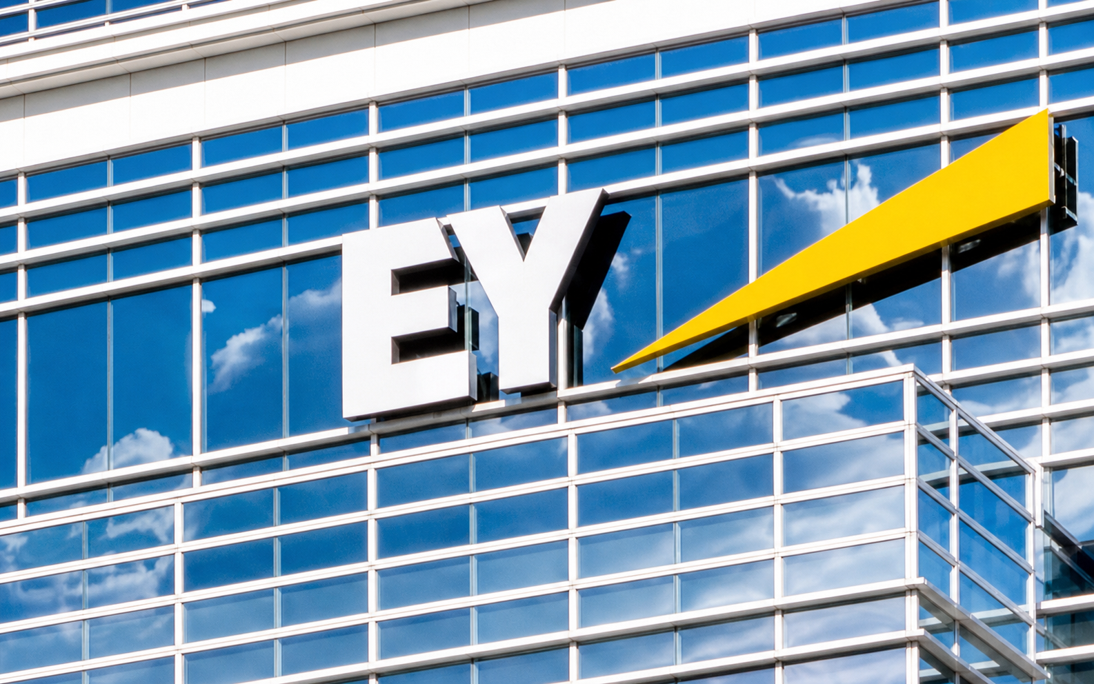 EY logo mounted on a glass office building